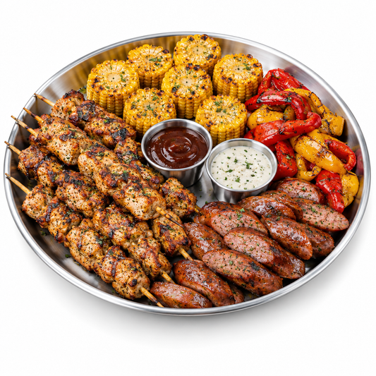 Large round stainless steel serving plate loaded with grilled skewers, sausages, corn, roasted peppers, and dipping sauces on pure white background