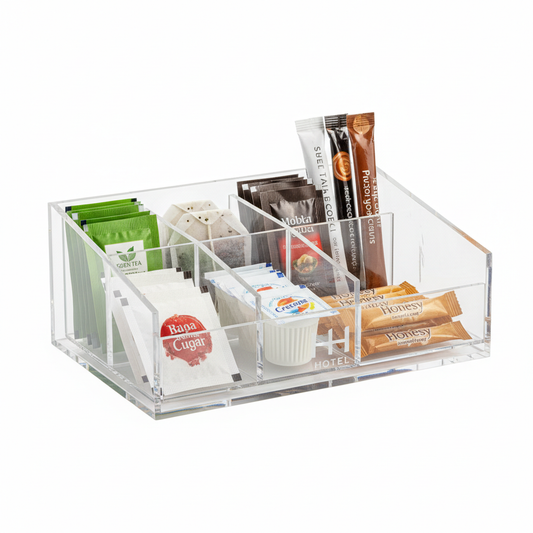 Clear acrylic hotel tea and coffee sachet holder with six compartments in two rows holding green tea black tea coffee stick sugar sachet creamer packet and honey stick with hotel logo on base panel on white background, compact hospitality guestroom beverage station organizer