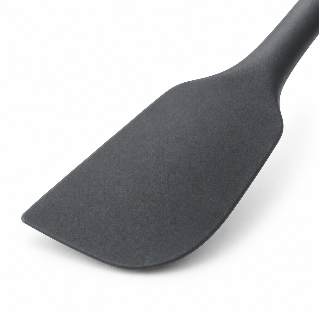 Close-up macro detail of flexible beveled scraper head and seamless food-grade silicone texture of kitchen spatula