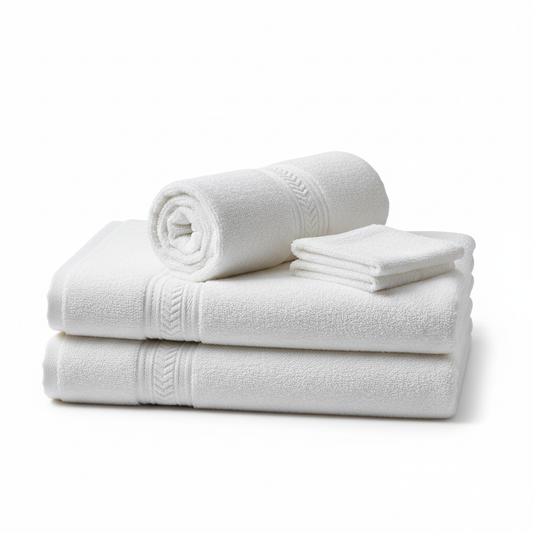 Coordinated set of three white cotton terry hotel spa towels in different sizes — bath towel folded stack, hand towel rolled cylinder and face towel square — showing matching jacquard border and dense terry loop pile on white background, premium hospitality spa linen set