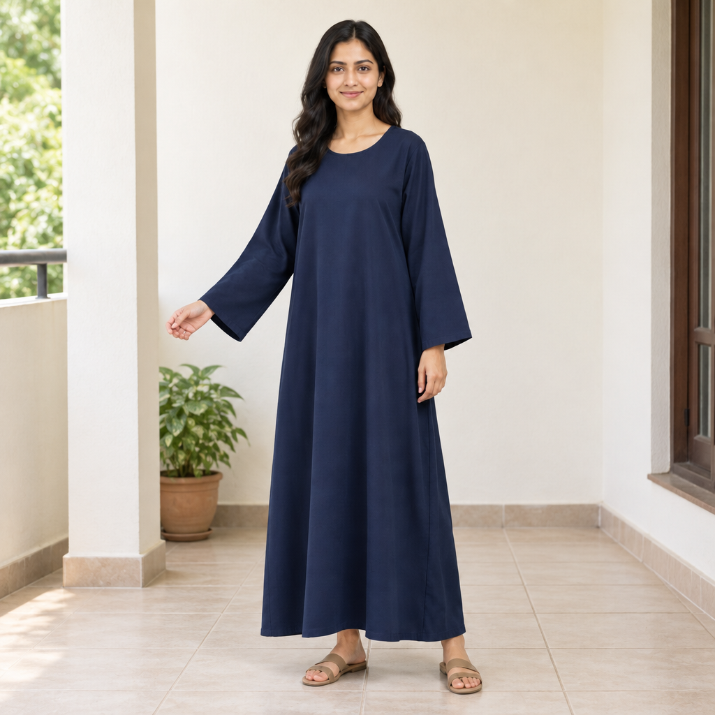 Model in a plain navy loose kaftan dress on a bright home veranda with one arm extended to show the sleeve