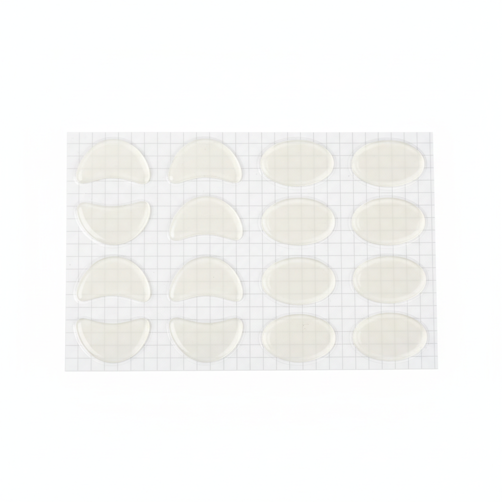 Self-adhesive silicone eyeglass nose pads on transparent backing liner sheet on white background