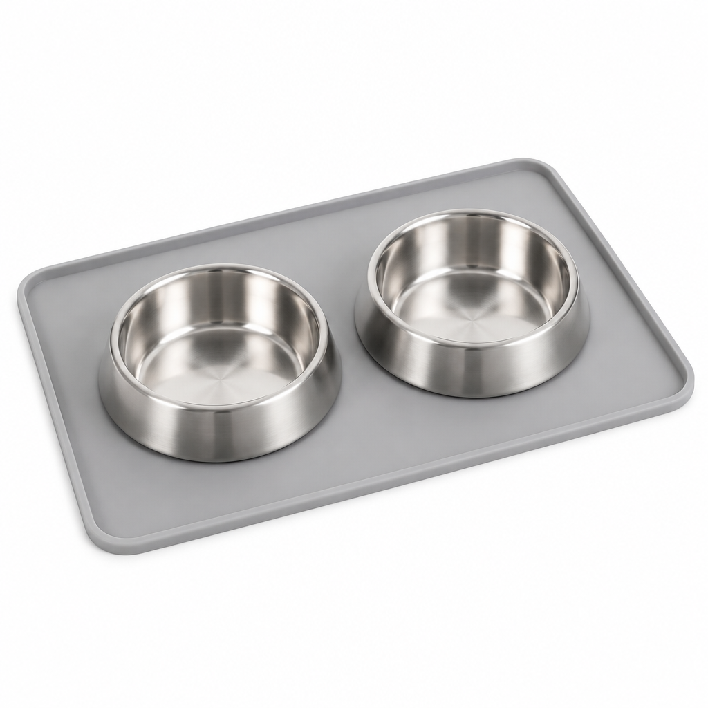 Light gray silicone pet feeding mat with raised spill edge and two stainless steel bowls on pure white background