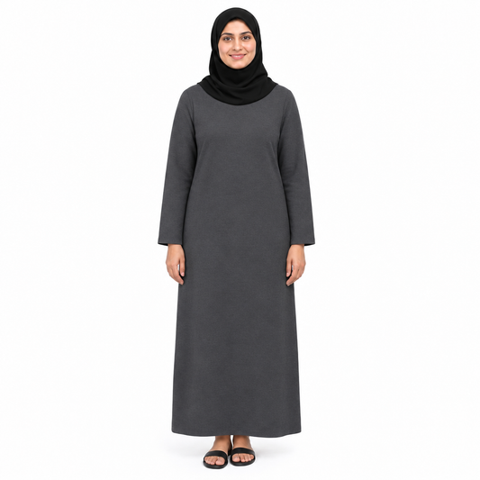 Model in a plain charcoal grey one-piece modest dress with long sleeves and relaxed full-length fit, front view on white
