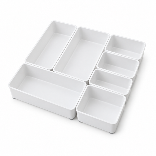 Drawer organizer tray set, white modular plastic trays in several sizes arranged in a grid on white background