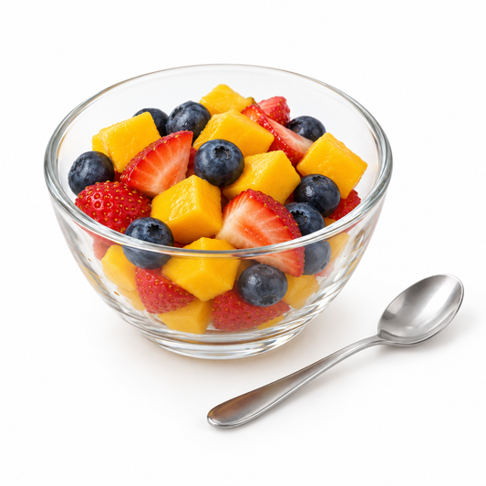 Round clear transparent glass dessert bowl filled with fresh diced fruit and dessert spoon on a seamless pure white background