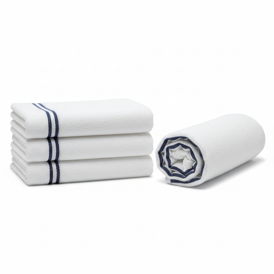 Large white cotton terry hotel pool towel with navy blue stripe border shown folded in thick rectangular stack and rolled cylinder on white background, commercial hospitality resort poolside beach towel