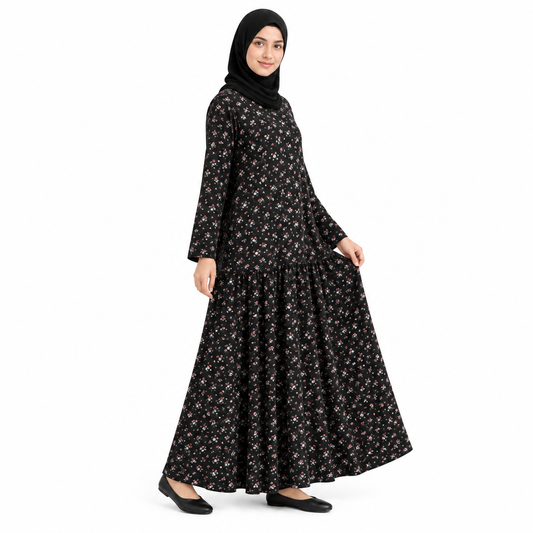 Angled full-length view of a black floral abaya maxi dress showing the long sleeves and gathered skirt on white