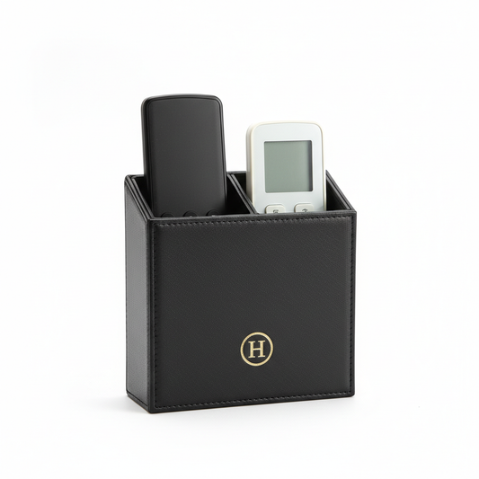 Black PU leather hotel remote control holder with two open slots holding slim TV remote and air conditioning remote with gold embossed hotel logo on front face on white background, compact hospitality guestroom bedside remote organizer