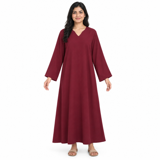 Front view of a model wearing a full-length plain burgundy loose kaftan dress with a shallow V-neck and long sleeves on white