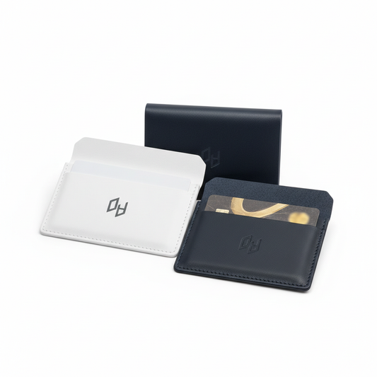 Two hotel key card holders side by side — white coated paper with minimal hotel logo print and dark navy PU leather — one open showing interior card slot with standard key card inserted and one closed, on white background, custom hospitality check-in stationery