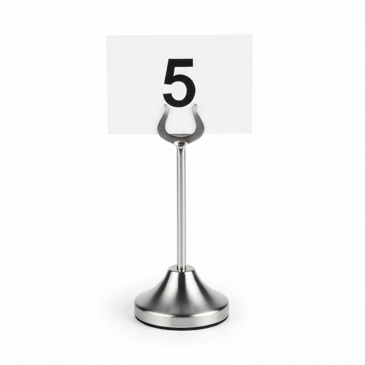Classic brushed stainless steel hotel restaurant table number stand approximately 10cm tall with heavy weighted flat round base and single vertical fork clip at top holding white card with number 5 on white background, commercial hospitality restaurant banquet event table identification stand