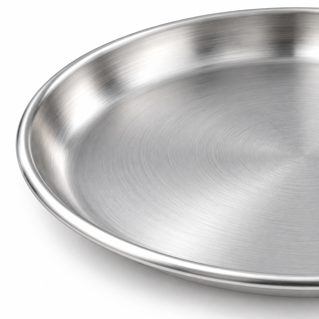 Macro close-up detail of the smooth rolled rim and brushed satin surface of a clean stainless steel dinner plate on white background