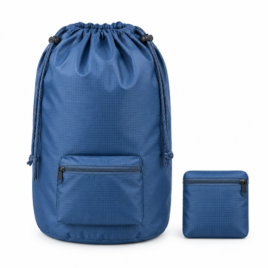Light navy blue ripstop travel laundry bag shown expanded beside a compact folded zippered pouch on white background