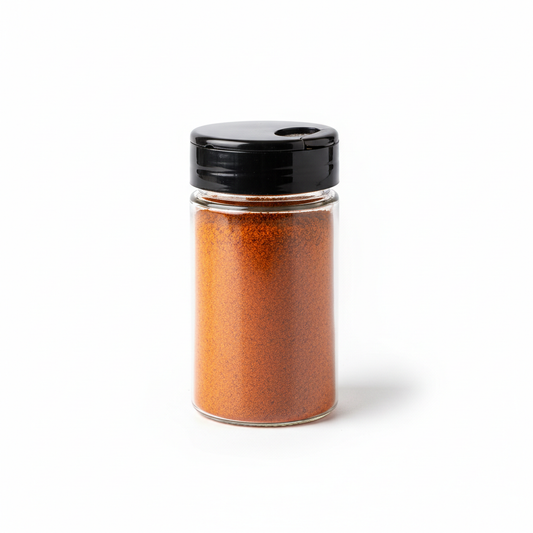 Clear spice storage container with black flip shaker lid filled with chili powder on pure white background