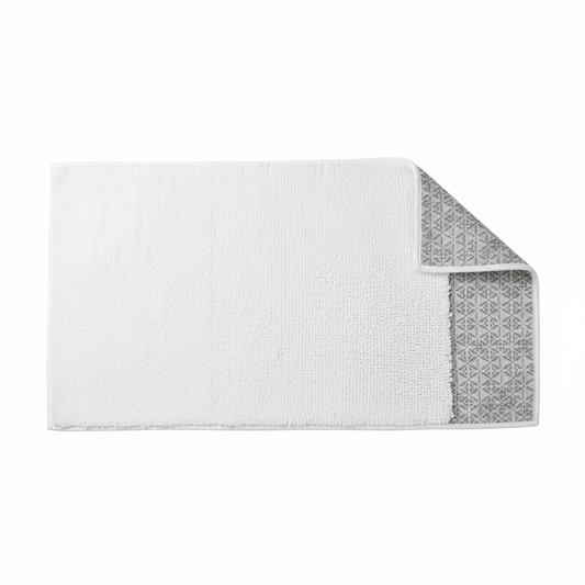 White thick absorbent hotel bath mat shown flat from overhead angle displaying full 50x80cm shape and dense plush pile surface with corner folded back revealing PVC anti-slip backing grid pattern on white background, commercial hospitality bathroom floor mat