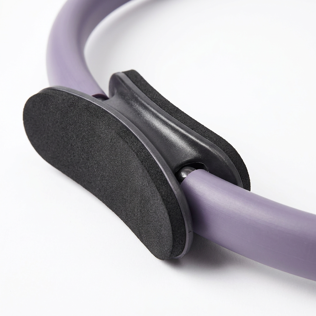 Detail close-up of Pilates ring dual-sided padded EVA handle and fiberglass ring joint on white background