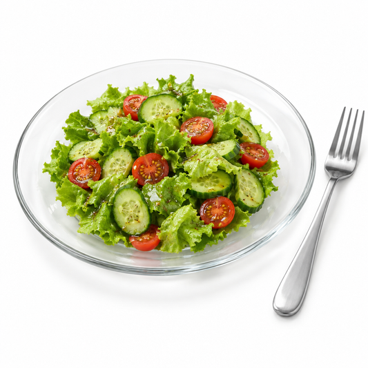 Round clear transparent glass dinner plate served with fresh green salad and fork on a seamless pure white background