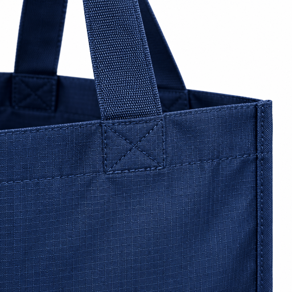 Close-up of the reusable shopping bag reinforced cross-stitching, webbing handle, and ripstop fabric